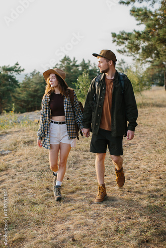 Couple in love, holding hands, walking while hiking on a mountain path.