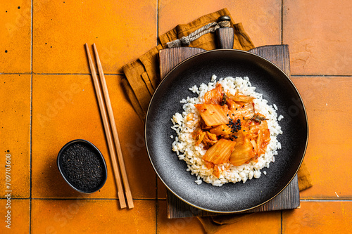 Kimchi with pork on cooked rice, traditional Korean cuisine. Orange background. Top view