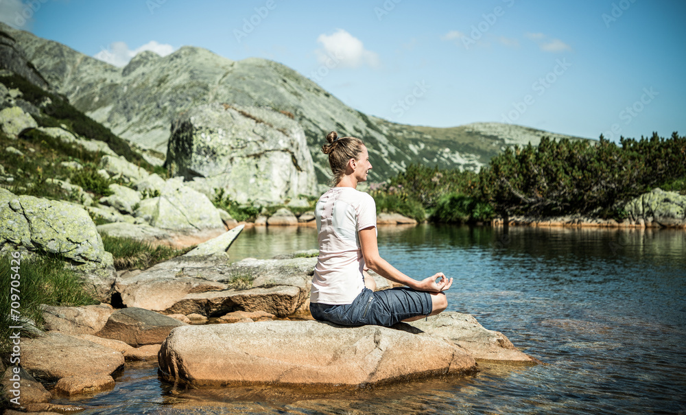 healthy young woman doing yoga in mountain landscape by lake