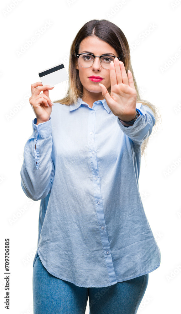 Young beautiful business woman holding credit card over isolated background with open hand doing stop sign with serious and confident expression, defense gesture Young beautiful business woman holding credit card over isolated background with open hand doing stop sign with serious and confident expression, defense gesture