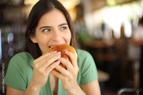 Happy woman eating burger in a restaurant