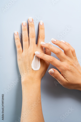 Woman smudging hand or body cream gel serum on her hands, body care concept
