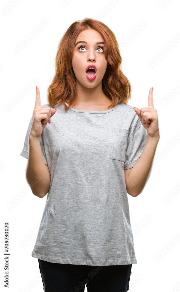 Young beautiful woman over isolated background amazed and surprised looking up and pointing with fingers and raised arms. Young beautiful woman over isolated background amazed and surprised looking up and pointing with fingers and raised arms.