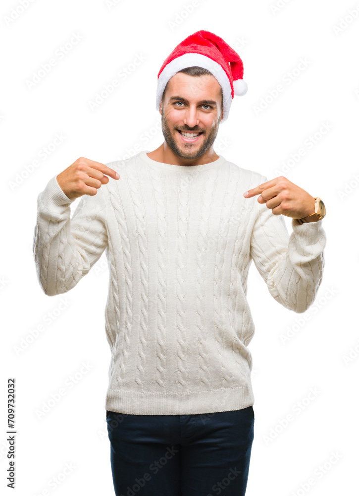 Naklejka premium Young handsome man wearing santa claus hat over isolated background looking confident with smile on face, pointing oneself with fingers proud and happy.