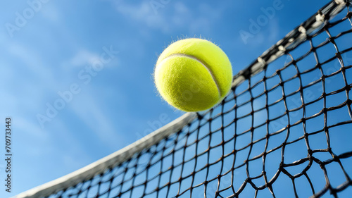 Yellow tennis ball and net on a blue sky background. Sport concept banner with copy space.Generative AI. © svf74