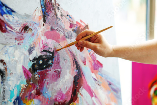 The hand with a brush draws a painting wih horse photo