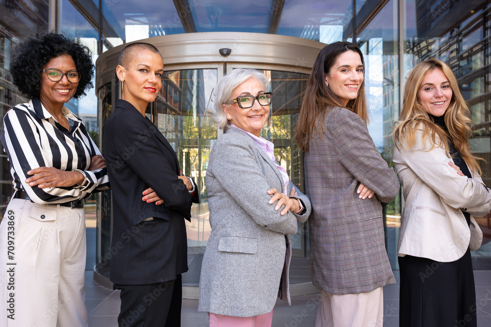 A team of multiracial and diverse businesswomen led with the boss posing one after the other for the camera.