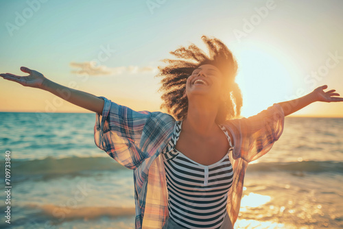 Joyful young woman with arms outstretched soaking up the sunshine on a serene beach, symbolizing freedom, happiness, or summer vacation photo