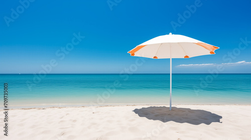 A solitary white and orange beach umbrella stands on a pristine sandy beach with a calm blue sea and clear sky in the background, conveying a tranquil vacation concept