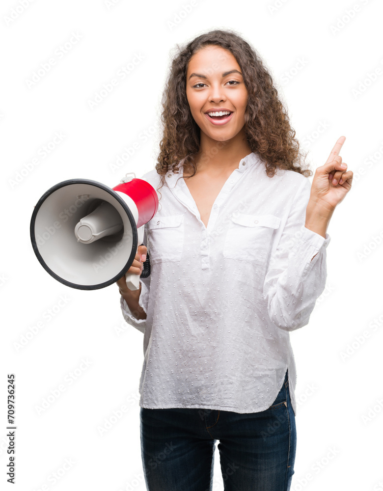 Young hispanic woman holding megaphone very happy pointing with hand and finger to the side Young hispanic woman holding megaphone very happy pointing with hand and finger to the side