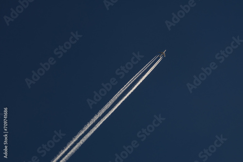 Flying airplane on the blue sky with white tale 