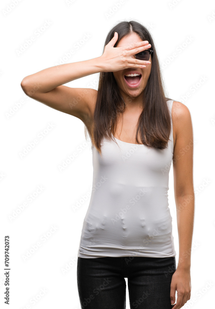 Young beautiful hispanic wearing sunglasses peeking in shock covering face and eyes with hand, looking through fingers with embarrassed expression. Young beautiful hispanic wearing sunglasses peeking in shock covering face and eyes with hand, looking through fingers with embarrassed expression.