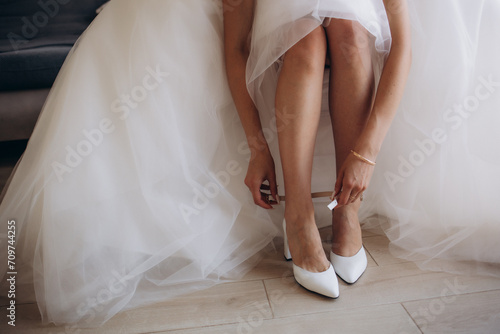 Bride puts on wedding shoes on her tender feet © Roman