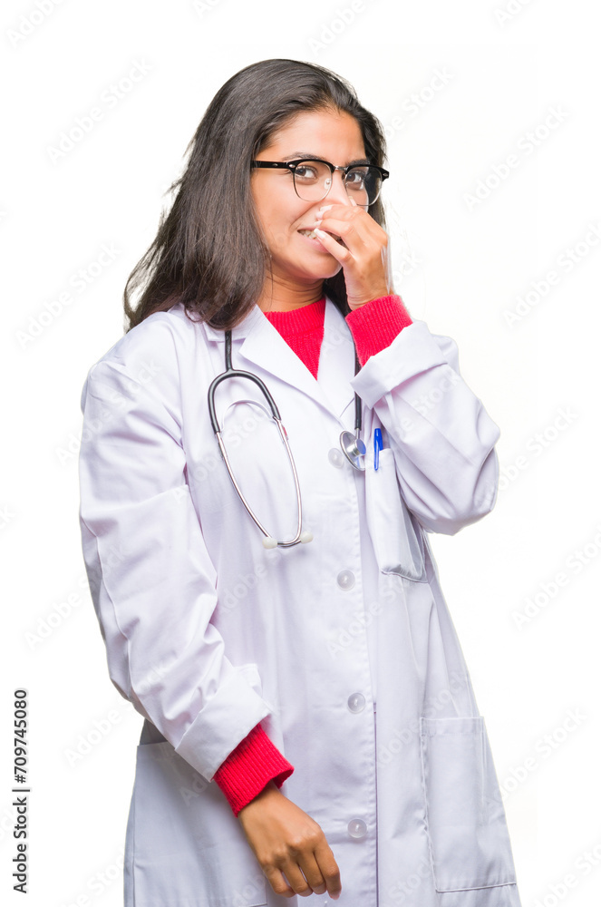 Young arab doctor woman over isolated background smelling something stinky and disgusting, intolerable smell, holding breath with fingers on nose. Bad smells concept. Young arab doctor woman over isolated background smelling something stinky and disgusting, intolerable smell, holding breath with fingers on nose. Bad smells concept.