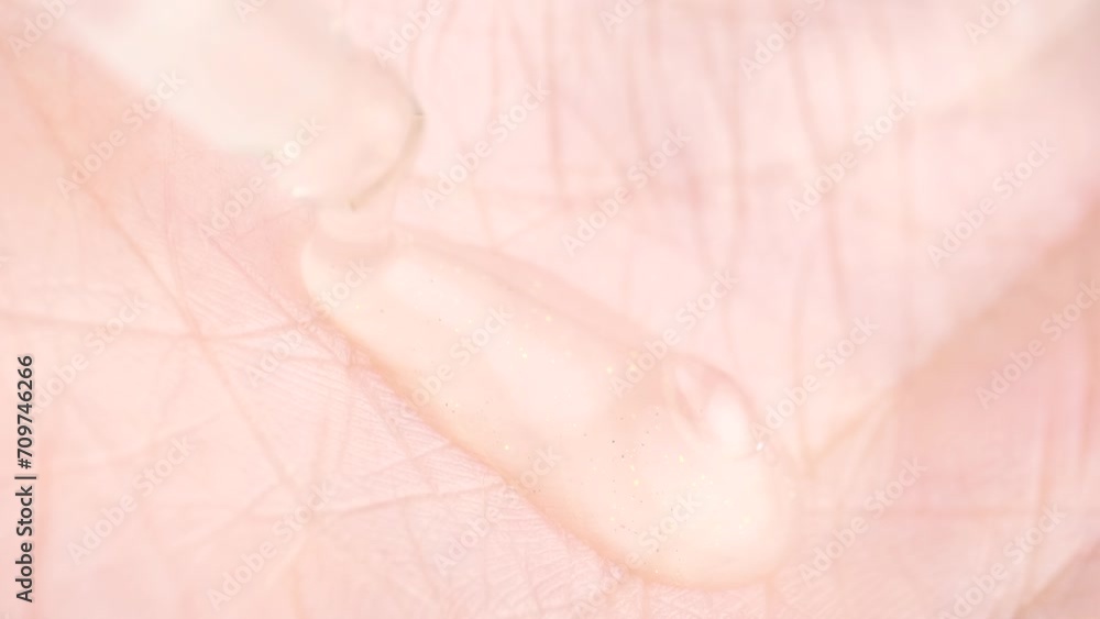 Close up of serum gel or oil falling on the skin. Macro shot of serum gel with golden shimmer in pipette falling on the palm. Health care cosmetics. Close up of serum gel or oil falling on the skin. Macro shot of serum gel with golden shimmer in pipette falling on the palm. Health care cosmetics.