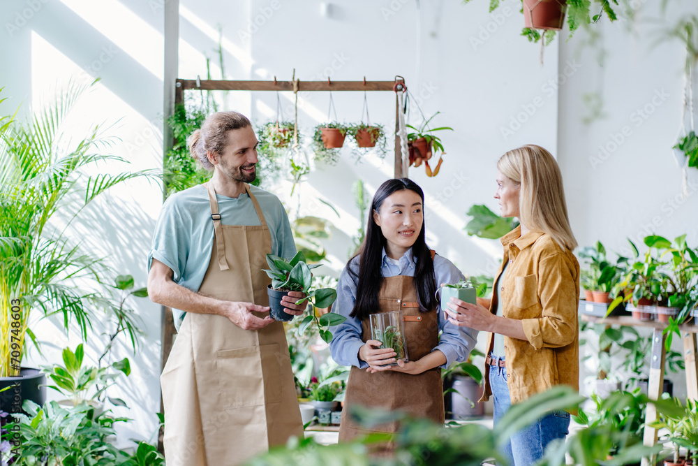 Obraz premium Welcoming two Florists owner, shop interior, seller, customer, potted plants. Floral business concept.