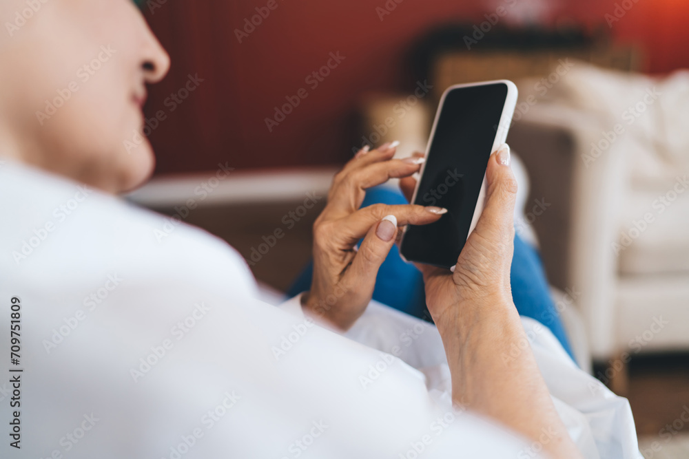 Crop woman using smartphone at blurred home Crop woman using smartphone at blurred home