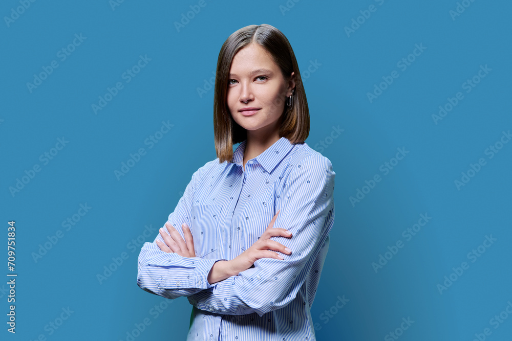 Portrait of confident young woman with crossed arms on blue background Portrait of confident young woman with crossed arms on blue background