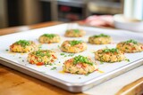 uncooked crab cakes prepped on parchment paper tray