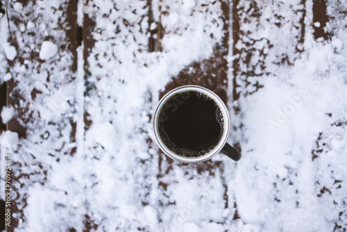 Coffee mug on snowy wooden table, outdoors