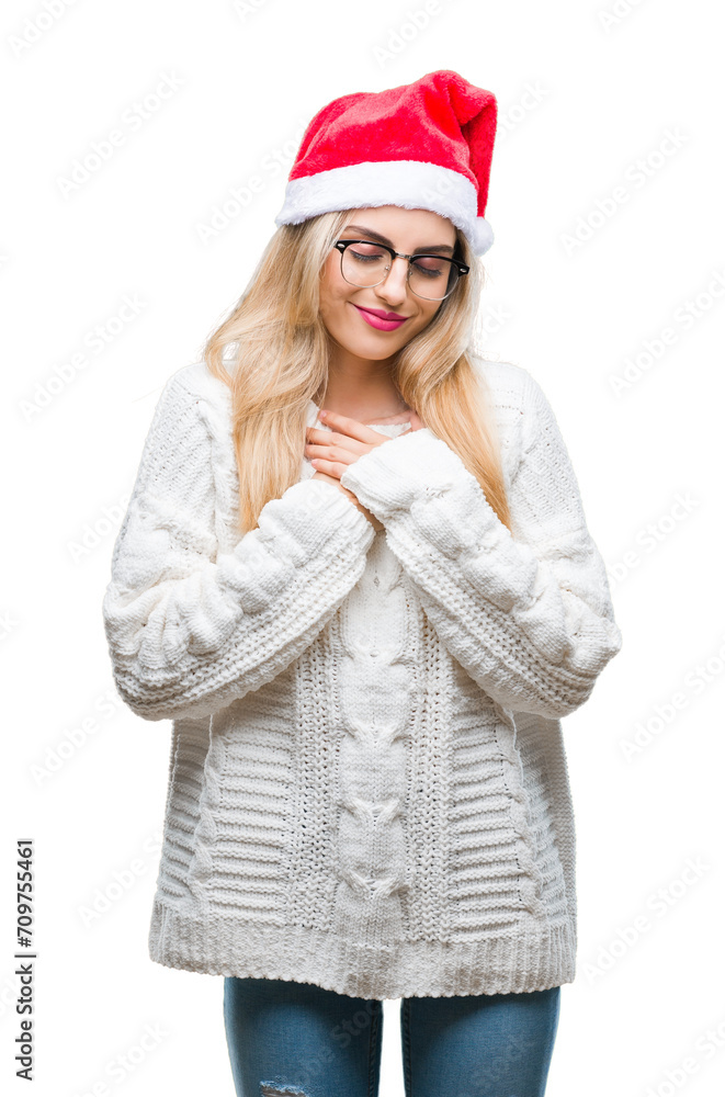 Young beautiful blonde woman wearing christmas hat over isolated background smiling with hands on chest with closed eyes and grateful gesture on face. Health concept. Young beautiful blonde woman wearing christmas hat over isolated background smiling with hands on chest with closed eyes and grateful gesture on face. Health concept.