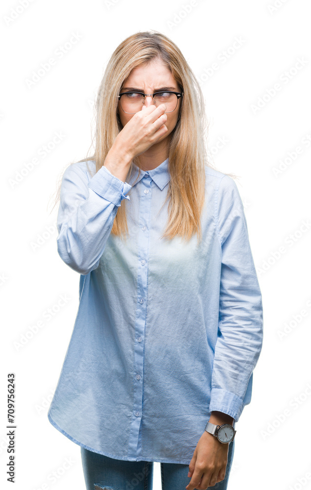 Young beautiful blonde business woman wearing glasses over isolated background smelling something stinky and disgusting, intolerable smell, holding breath with fingers on nose. Bad smells concept.