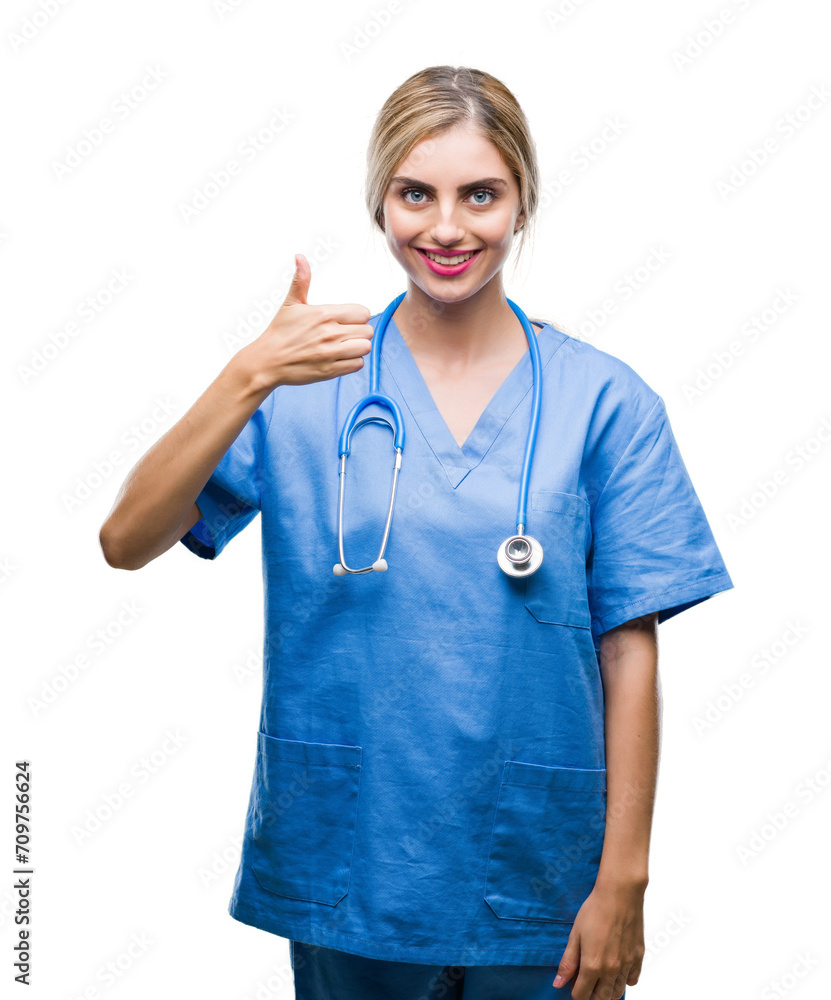 Young beautiful blonde doctor surgeon nurse woman over isolated background doing happy thumbs up gesture with hand. Approving expression looking at the camera with showing success. Young beautiful blonde doctor surgeon nurse woman over isolated background doing happy thumbs up gesture with hand. Approving expression looking at the camera with showing success.