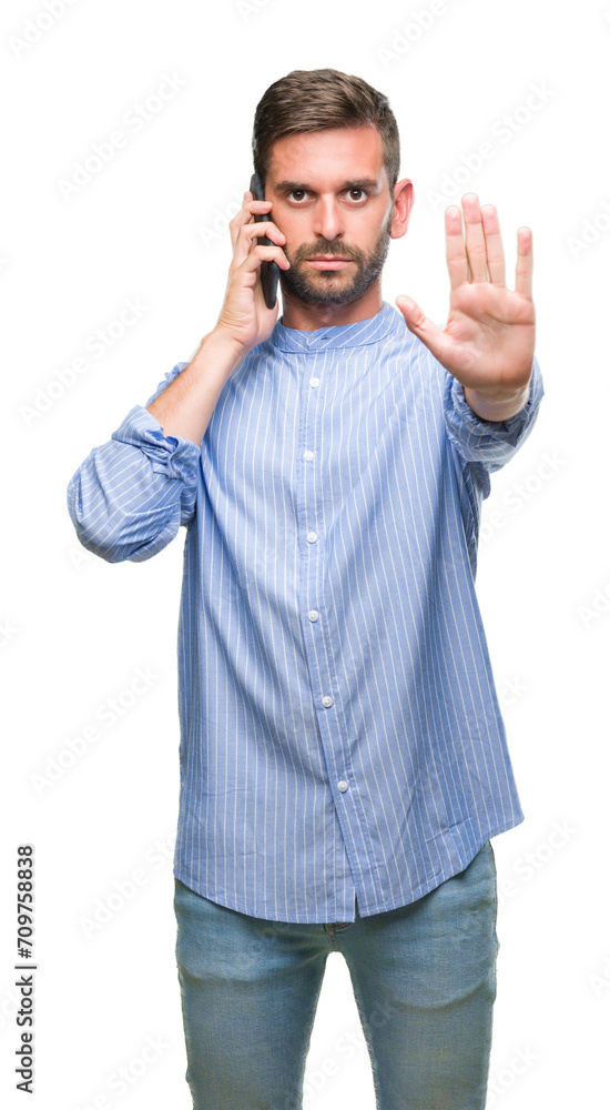 Fototapeta premium Young handsome man speaking on the phone over isolated background with open hand doing stop sign with serious and confident expression, defense gesture