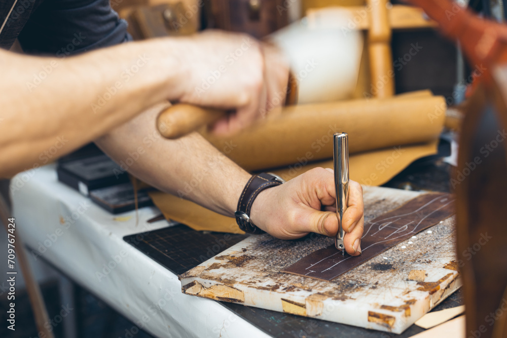 Close up of a shoemaker or artisan worker hands. Leather craft tools on old wood table. Close up of a shoemaker or artisan worker hands. Leather craft tools on old wood table.