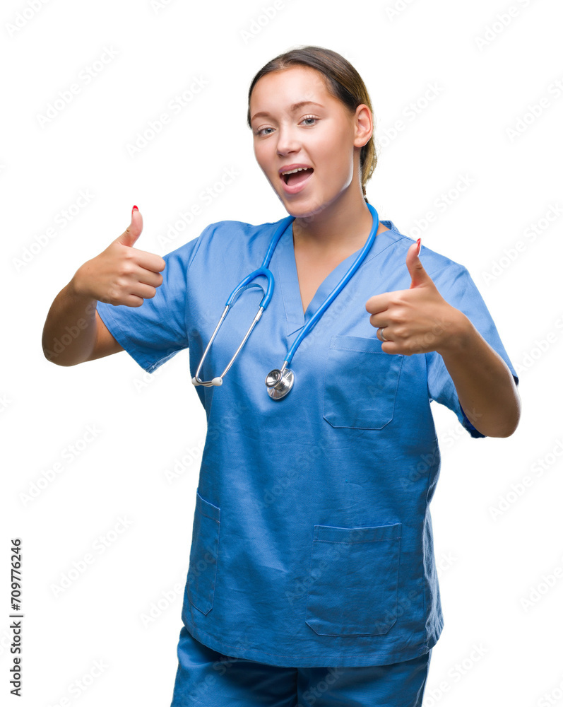 Young caucasian doctor woman wearing medical uniform over isolated background approving doing positive gesture with hand, thumbs up smiling and happy for success. Looking at the camera. Young caucasian doctor woman wearing medical uniform over isolated background approving doing positive gesture with hand, thumbs up smiling and happy for success. Looking at the camera.