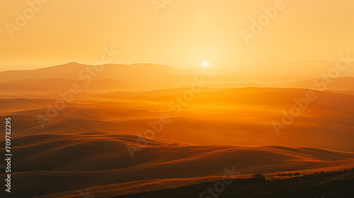 Dramatic sunset over a rolling hills landscape with long shadows and a golden sky.