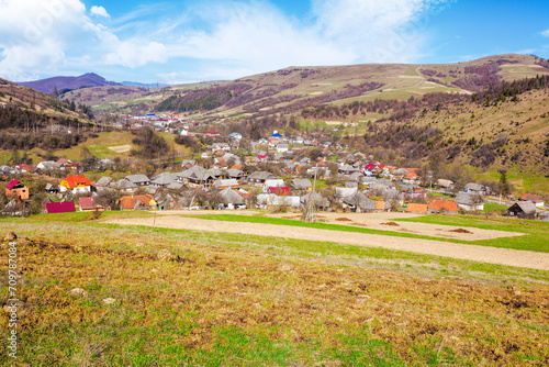 carpathian countryside scenery with fields on the hills and village in the valley. mountainous rural landscape of ukraine on a sunny day in spring