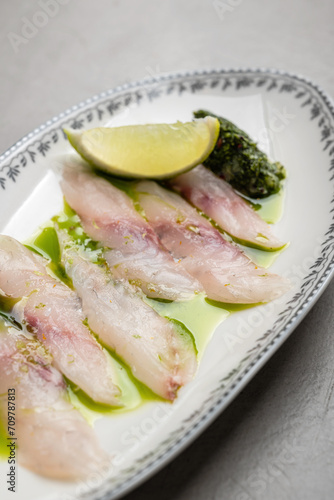 Seabass carpaccio with lime and green oil dressing, close-up