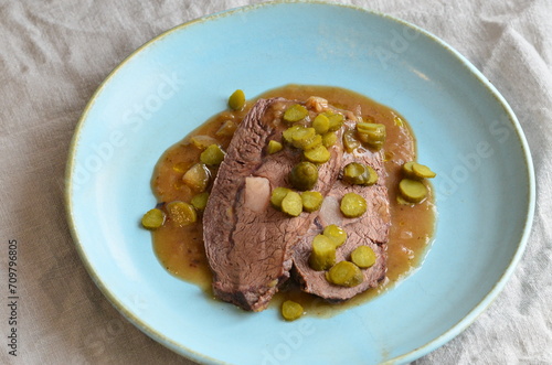 beef stew with pickled green cucumber and serving on a blue plate, czech food