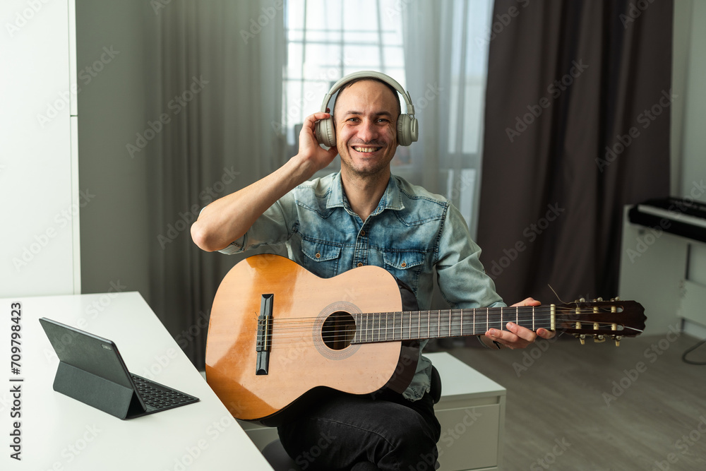 Obraz premium The guy in live online live records podcasts, plays guitar. He communicates with people, smiles, and runs his own music blog.