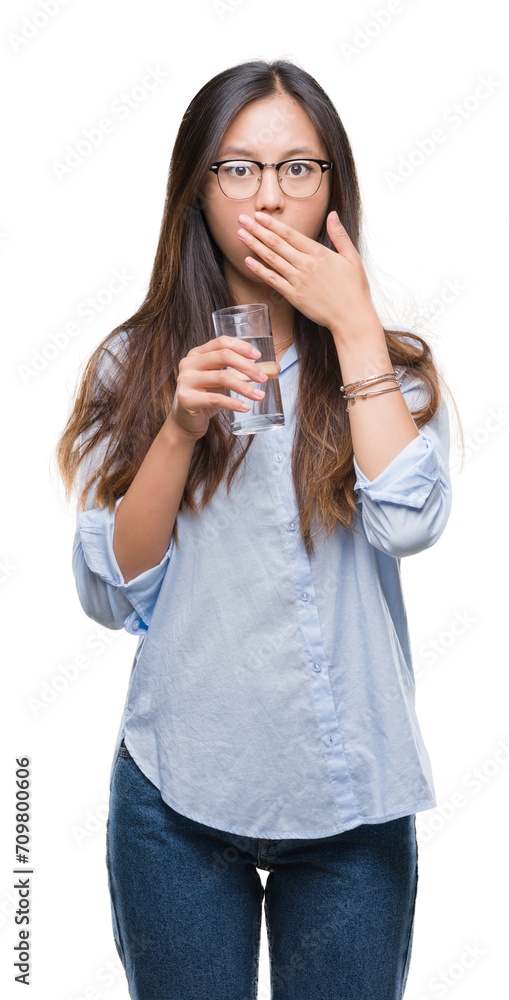 Young asian woman drinking a glass of water over isolated background cover mouth with hand shocked with shame for mistake, expression of fear, scared in silence, secret concept Young asian woman drinking a glass of water over isolated background cover mouth with hand shocked with shame for mistake, expression of fear, scared in silence, secret concept