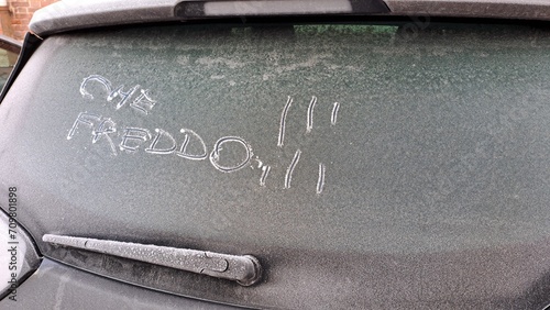 Che freddo ! scritta italiano sul lunotto posteriore di un'auto coperta da ghiaccio. photo