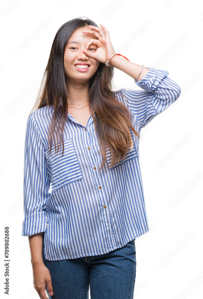 Young asian woman over isolated background doing ok gesture with hand smiling, eye looking through fingers with happy face. Young asian woman over isolated background doing ok gesture with hand smiling, eye looking through fingers with happy face.