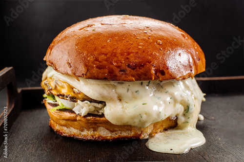 Juicy fresh burger with melted mozzarella cheese on a dark background