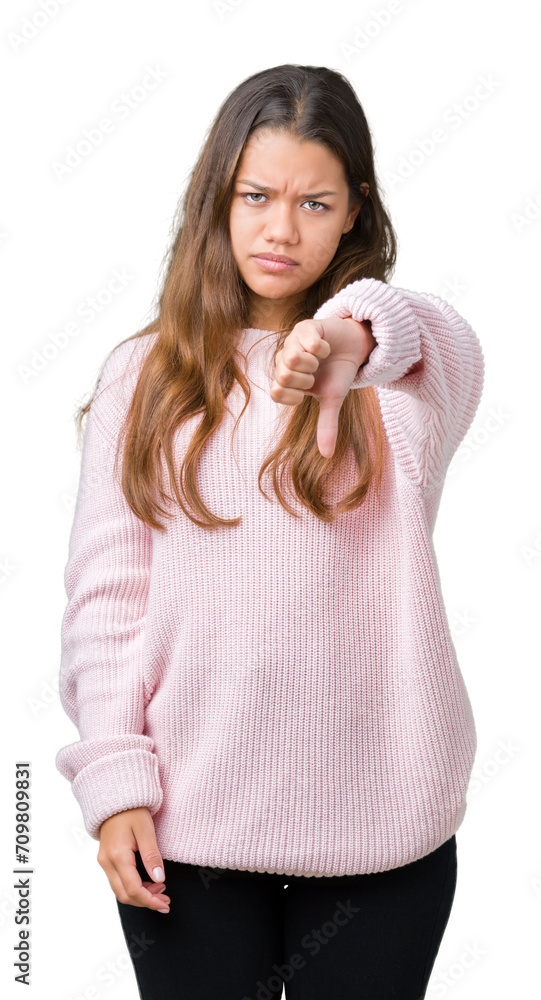Young beautiful brunette woman wearing pink winter sweater over isolated background looking unhappy and angry showing rejection and negative with thumbs down gesture. Bad expression. Young beautiful brunette woman wearing pink winter sweater over isolated background looking unhappy and angry showing rejection and negative with thumbs down gesture. Bad expression.
