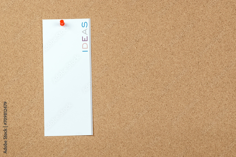 Blank notice with the word ideas printed in vertical on it pinned to a cork board. Copy space. Blank notice with the word ideas printed in vertical on it pinned to a cork board. Copy space.