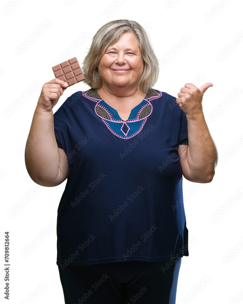 Obraz premium Senior plus size caucasian woman eating chocolate bar over isolated background pointing and showing with thumb up to the side with happy face smiling