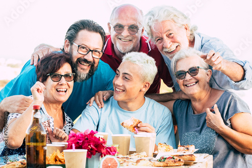 Family generations enjoy and celebrate with fun all together laughing and smiling posing for a picture outdoor at home - table full of food and drinks to eat for caucasian people