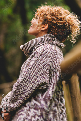 Side portrait of woman relaxing in the nature. Inner balance and mindfulness concept moments. Standing female people in the woods enjoying silence and good nature vibes alone smiling and admiring