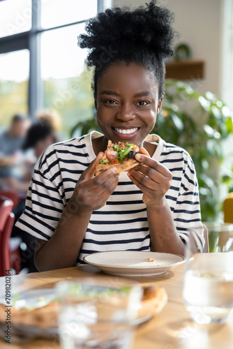 Cute dark-skinned young woman enjoying pizza
