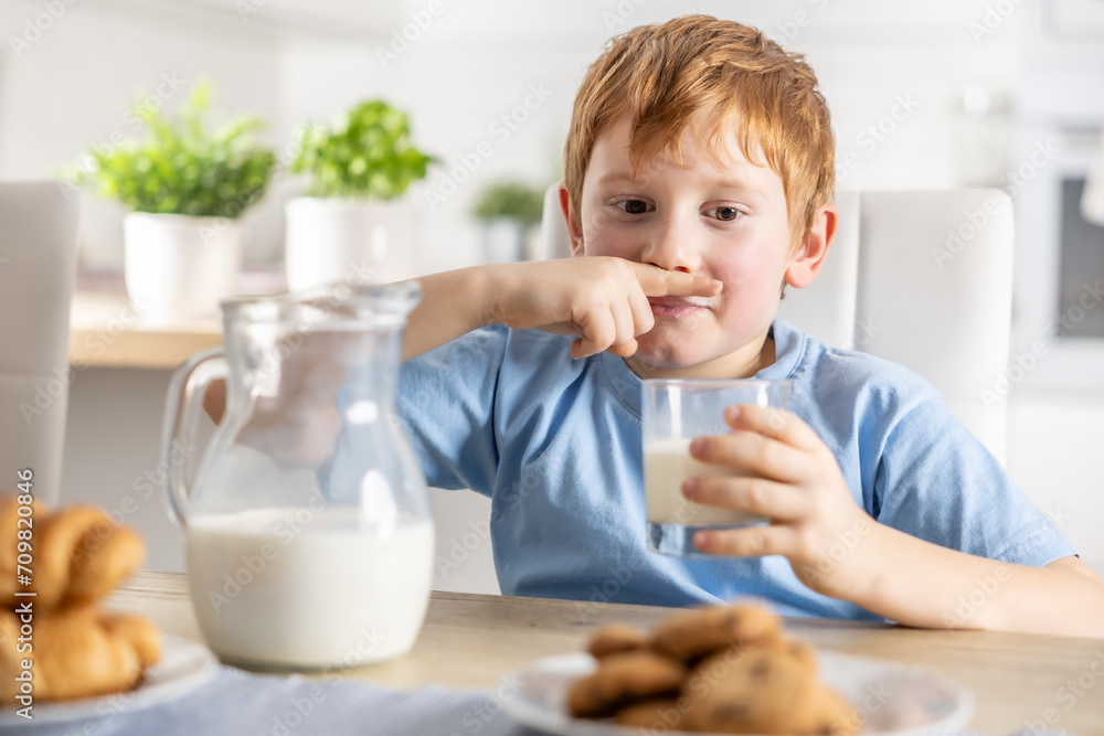 A cute little boy is wiping his milky mustache because he drank his favorite drink A cute little boy is wiping his milky mustache because he drank his favorite drink
