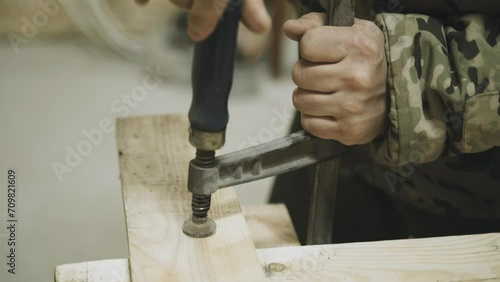 A carpenter secures a piece of wood using a screw clamp. Fastening the part. Close-up. photo
