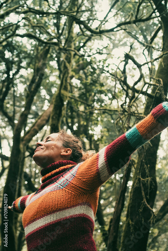 Happy adult woman smile and open arms to embrace beautiful nature forest around her. Concept of green ambient and sustainable tourism travel people. Earth's day and love for woods concept