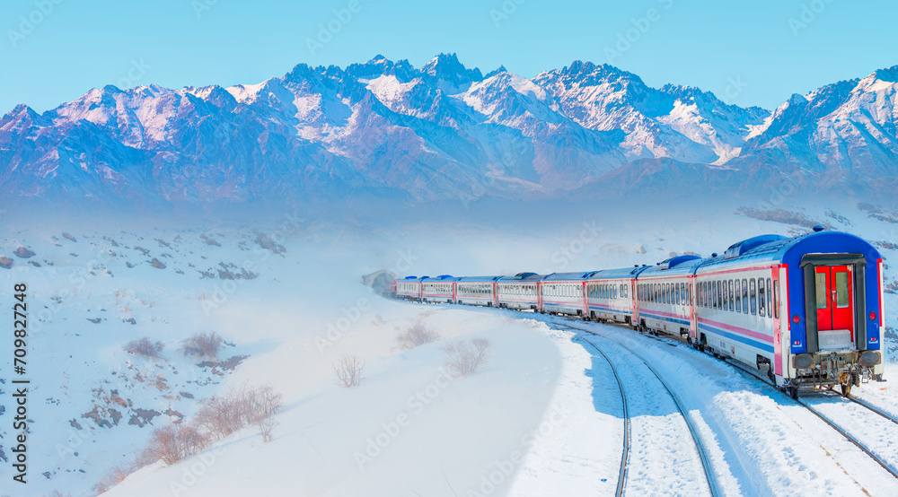 Red diesel train (East express) in motion at the snow covered railway platform - The train connecting Ankara to Kars - Passenger train going through tunnel  - obrazy, fototapety, plakaty 