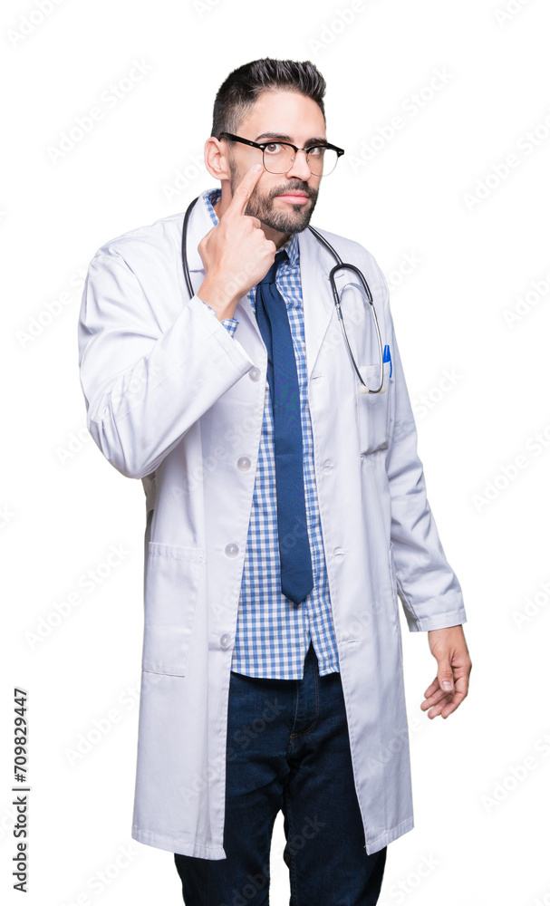 Handsome young doctor man over isolated background Pointing to the eye watching you gesture, suspicious expression Handsome young doctor man over isolated background Pointing to the eye watching you gesture, suspicious expression
